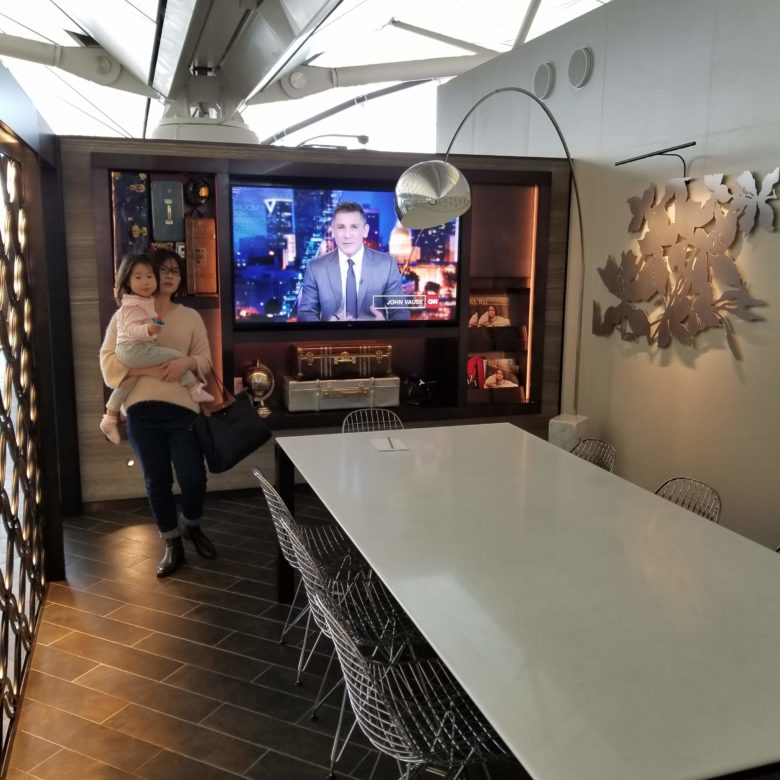 香港国際空港のセンチュリオンラウンジの大きなテーブルのある部屋のテレビ